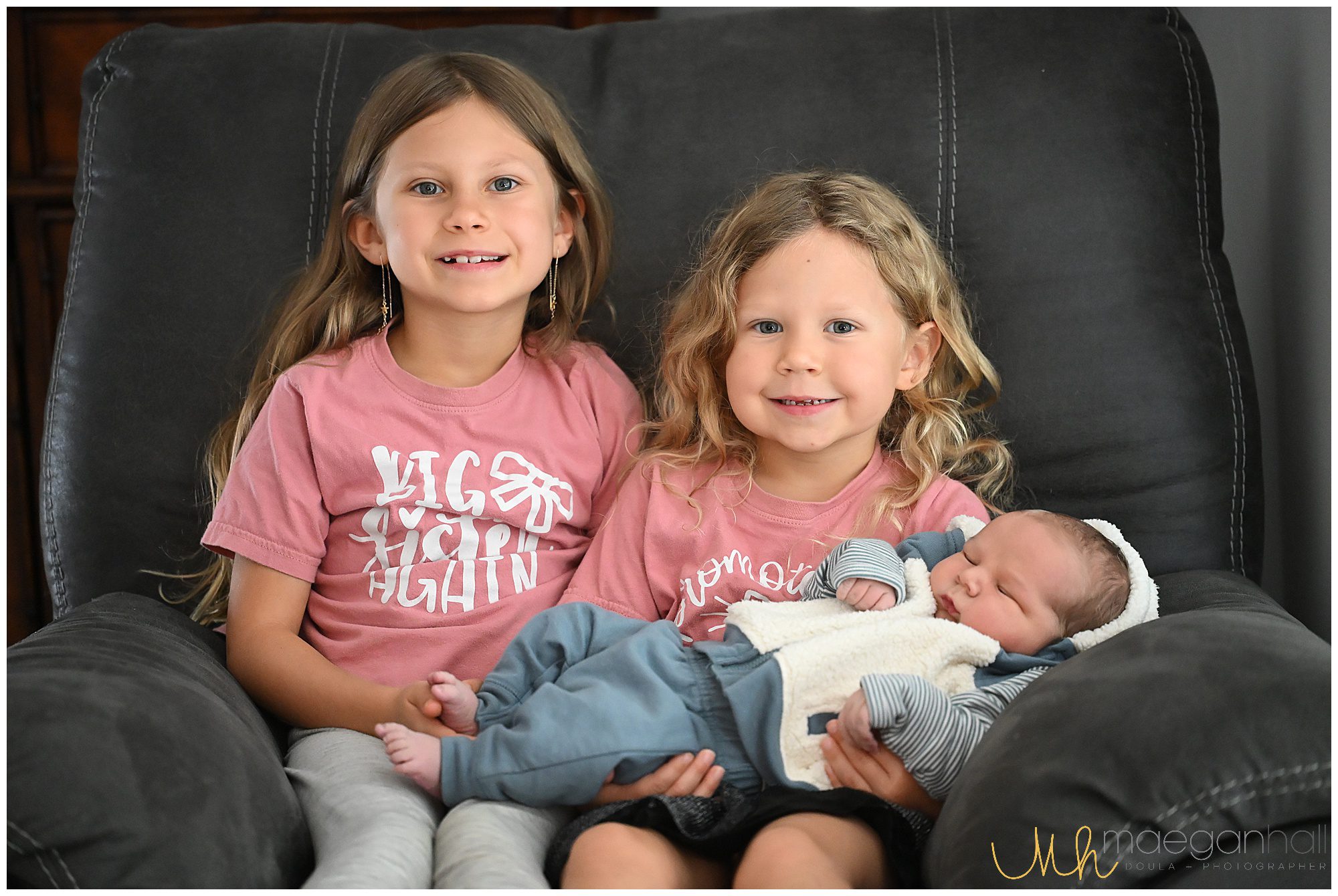 Sisters hold their new baby brother