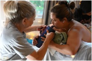 mother gives her laboring daughter water while in the birth pool